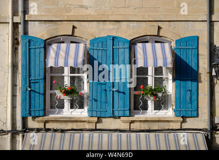 Typical house in Arles, Provence, with blue shutters and window boxes with geraniums on a bright sunny afternoon Stock Photo
