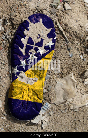 The flag of Bosnia and Herzegovina is depicted on the sole of an old boot. Ecology concept with environmental pollution from household and industrial Stock Photo