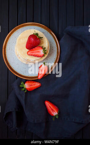 Flat lay view of appetizing vanilla rice cakes with fresh strawberries on black background. Stock Photo