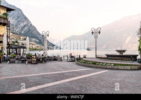 Pastel hues as we look over Piazza Garibaldi & Lake Garda.  A ferry is crossing the lake and to the left is a seating area for Ristorante Gemma. Stock Photo