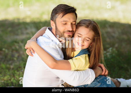 Little girl hugging her father, having picnic outdoors Stock Photo