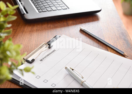 Folder with paper questionnaire on wooden table in office. Horizontal composition. Elevated view. Stock Photo