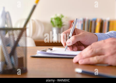 Man filling out a questionnaire on a wooden table close up. Horizontal composition. Front view. Stock Photo