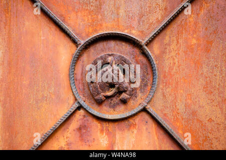 Horse head framed in horseshoe on close up of old rusted abandoned metal door Stock Photo
