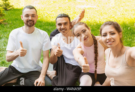 Smiling yoga students showing thumbs up after practicing. Stock Photo