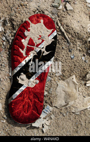 The flag of Trinidad and Tobago is depicted on the sole of an old boot. Ecology concept with environmental pollution from household and industrial was Stock Photo