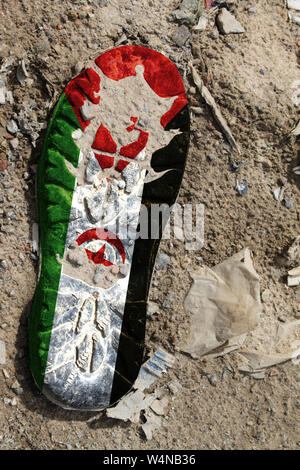 The flag of Western Sahara is depicted on the sole of an old boot. Ecology concept with environmental pollution from household and industrial waste. Stock Photo