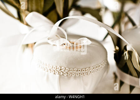 Closeup of gold wedding rings tied with a white silk ribbon to a jewelry box, selective focus Stock Photo