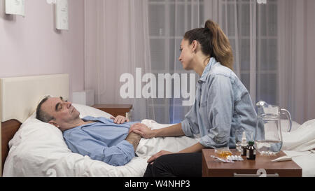 Daughter visiting elderly father in hospital and medical worker talking to them Stock Photo