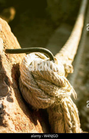 Tick cord or a rope maybe from big ship or boat tied on the steel hook embarked in stone Stock Photo