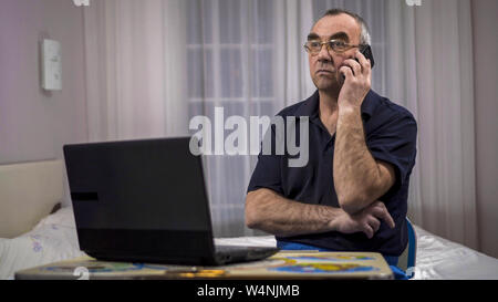 Elderly grey-haired male using laptop, watching football on a laptop and gets upset Stock Photo