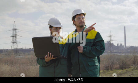 Workers in production plant as team discussing, industrial scene in background Stock Photo