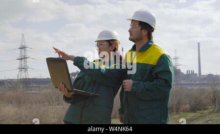 Workers in production plant as team discussing, industrial scene in background Stock Photo