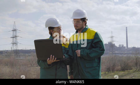 Workers in production plant as team discussing, industrial scene in background Stock Photo
