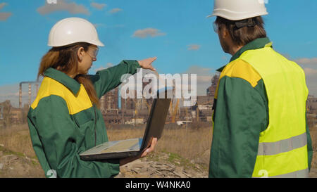 Workers in production plant as team discussing, industrial scene in background Stock Photo