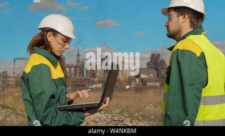 Workers in production plant as team discussing, industrial scene in background Stock Photo