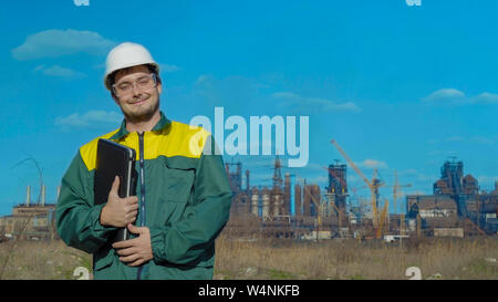The male engineer projects the work. Sunny day and clouds. The man is dressed in a green sunglass vest Stock Photo