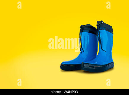 Blue rubber boots isolated	on yellow background Stock Photo