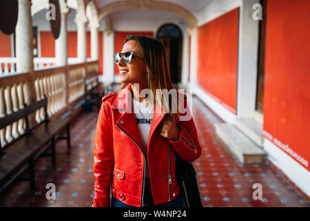 Close-up portrait of cheerful white woman in sunglasses. Photo of fashionable girl with red leather jacket. Stock Photo