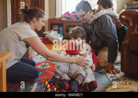 A family wrestles together on the living room floor Stock Photo