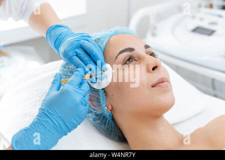 The beautician makes professional rejuvenation vitamin injections for the skin of the patient's face. A young girl is undergoing a course of spa treat Stock Photo