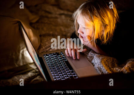 Kid using laptop computer in bed Stock Photo
