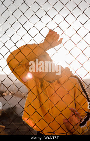 Young woman behind bars on a sunset. Lifestyle concept, model. Stock Photo