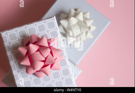 Three light gray gift boxes with colorful bows on pink background. Festive concept. Stock Photo