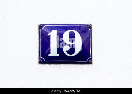 House number 19 with the nineteen on a blue enamel sign on a white wall Stock Photo