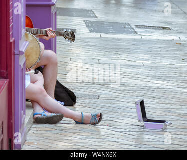 Unrecognizable street musicians, playing guitar, tambourine and asking for money in the street. Stock Photo