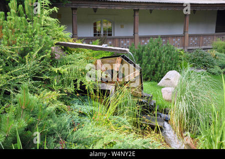 Landscape and arrangement. Driving mill wheel with falling water in the garden. Stock Photo