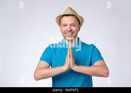 Man in blue shirt holding hands in Namaste welcoming guests Stock Photo