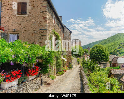 Conques, Midi Pyrenees, France - July 31, 2017: Typical narrow stone streets in the village of Conques decorated with colorful flowers Stock Photo