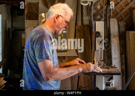 Side view of an elderly gentleman cutting wood with a band saw Stock Photo