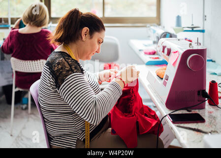 Using measuring tape. Seamstress is in her office that is with