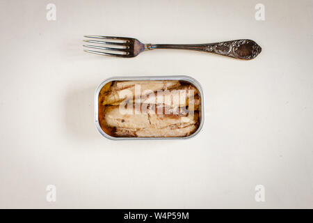 sardines in a tin and rustic fork on white table background Stock Photo