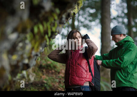 Young man looking in backpack of girlfriend while on a hike. Stock Photo