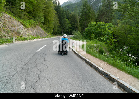 disabled person in an electric wheelchair driving on the street, road Stock Photo