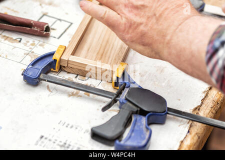 Senior carpenter glueing wooden craft surface and joining with clamps. Woodwork carpenter with equipment and tools at workshop. Handmade diy furniture Stock Photo