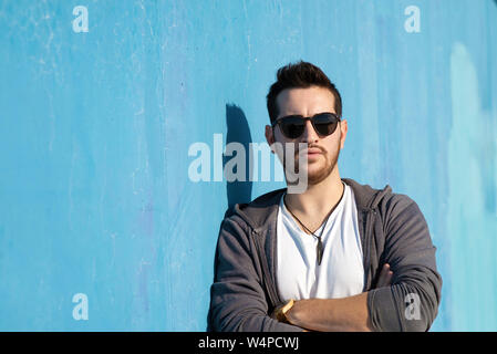 Portrait of young bearded man with sunglasses leaning against wall Stock Photo