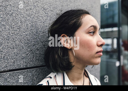 Side view of sas young woman face leaning on wall in the city. Stock Photo