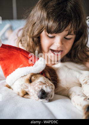 English setter puppy with santa claus hat and little girl smiling Stock Photo