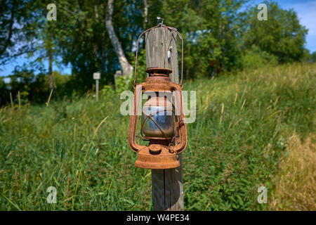 old gas kerosene lamp hanging on a wooden pole on a grass hill. Stock Photo