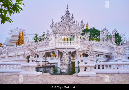 Enjoy the picturesque Rebirth Cycle bridge and ornate Gate of Heaven, surrounded by Naga serpent sculptures, White Temple, Chiang Rai, Thailand Stock Photo