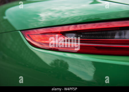 Back of a luxury green sports car. Closeup of a modern red backlight. Beautiful car body. Stock Photo