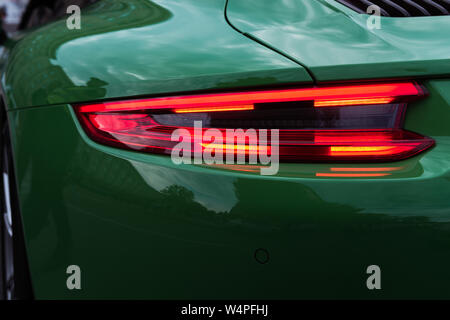 Green sports car. Car backlight on. Closeup of a modern red LED light.  Back of a luxury car. Beautiful car body. Stock Photo