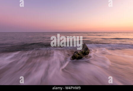 Beautiful shot of the ocean and a driftwood  at sunset.Long exposure with copy space Stock Photo