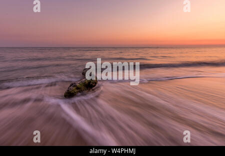 Beautiful shot of the ocean and a driftwood  at sunset.Long exposure with copy space Stock Photo