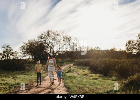 Front view of mother, son, and daughter walking in sunny field Stock Photo