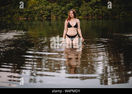 Front view of young woman standing in lake Stock Photo